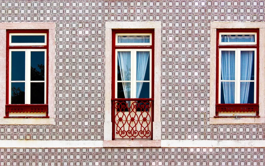 Alfama: Three red‑framed windows on patterned tiled façade