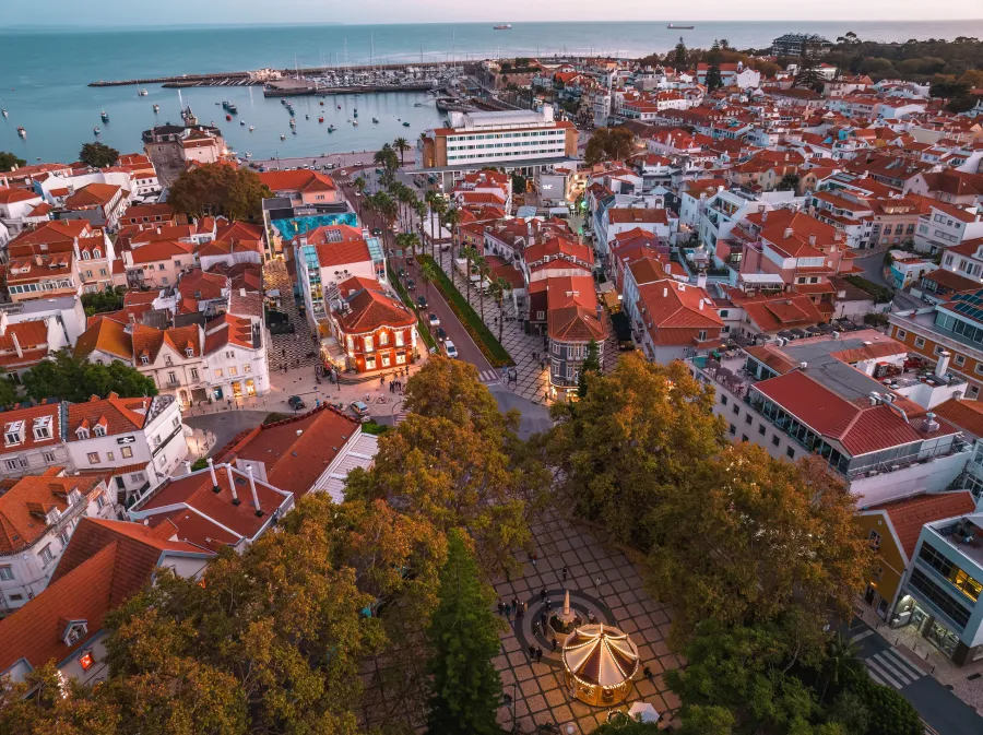 Cascais: Aerial view of a coastal town with red roofs, a harbor full of boats and a central plaza