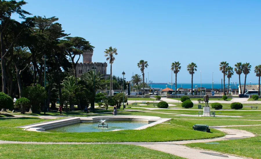Coastal park with green lawns, palm trees, a fountain and ocean views