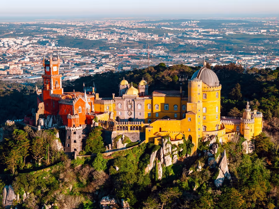 Colorful hilltop Pena Palace rising above Sintra’s forests with sweeping views over the landscape