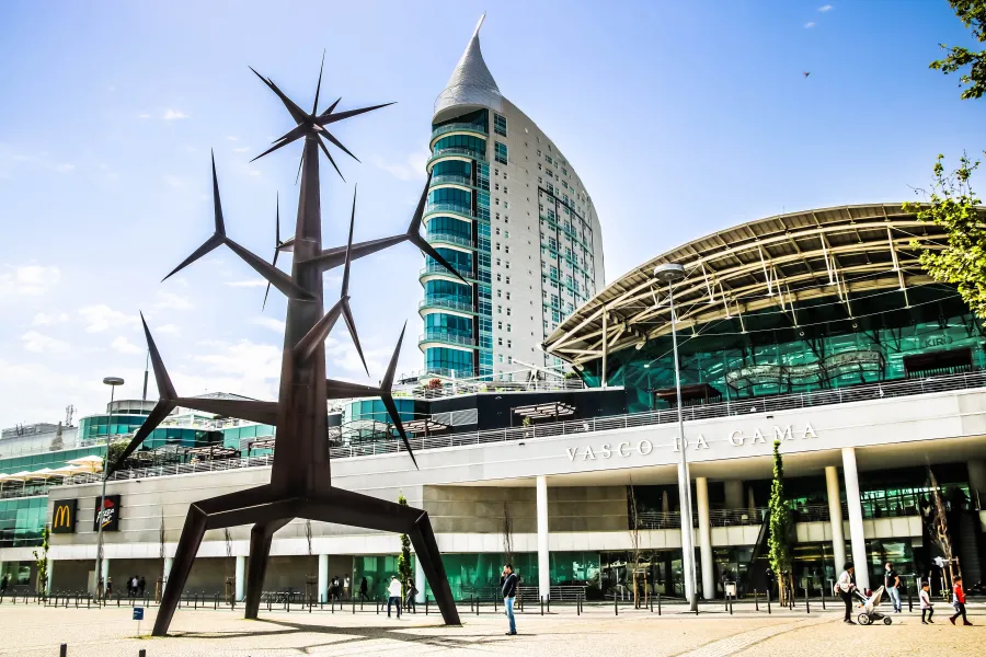 Modern plaza with a large metal sculpture and the Vasco da Gama building in the background