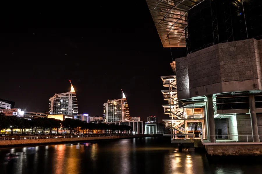 Parque das Nações: Night waterfront with modern glass buildings reflecting lights over calm water