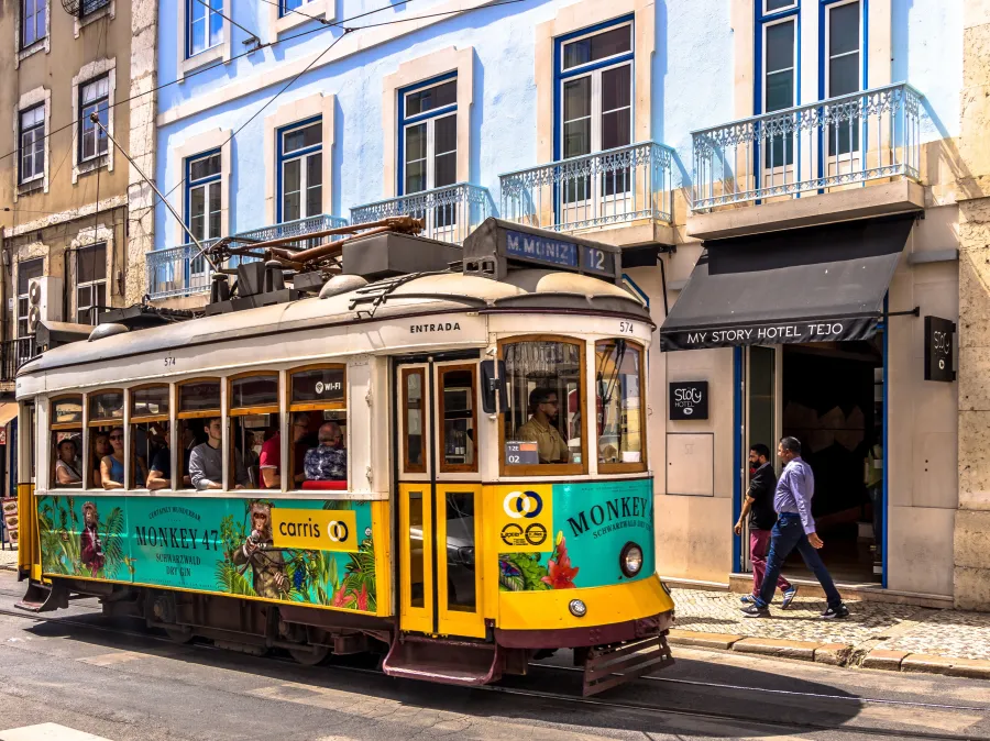 Yellow Lisbon tram passing a blue building with hotel signage in Alfama